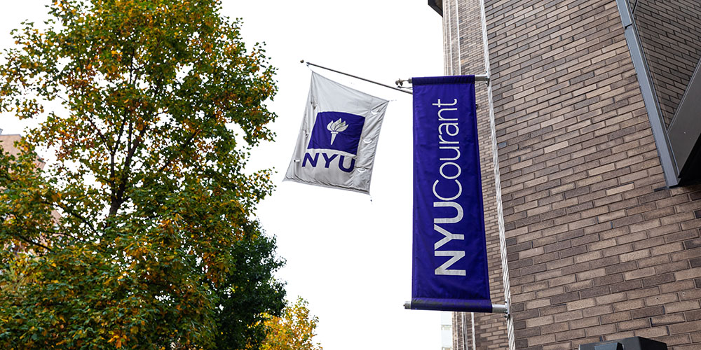 纽约大学柯朗数学、计算与数据科学学院大楼外观,NYU Courant校旗与标志性蓝色横幅悬挂于教学楼外墙
