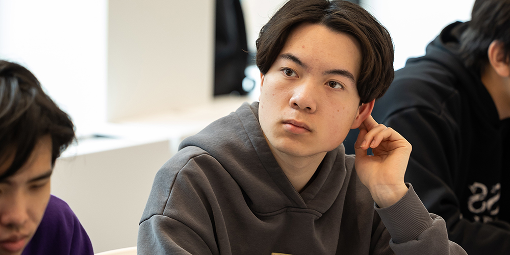 纽约大学柯朗数学计算与数据科学学院数据科学博士课程介绍,亚洲男学生认真聆听课堂讲解,展示数据科学博士学术氛围与多元文化环境